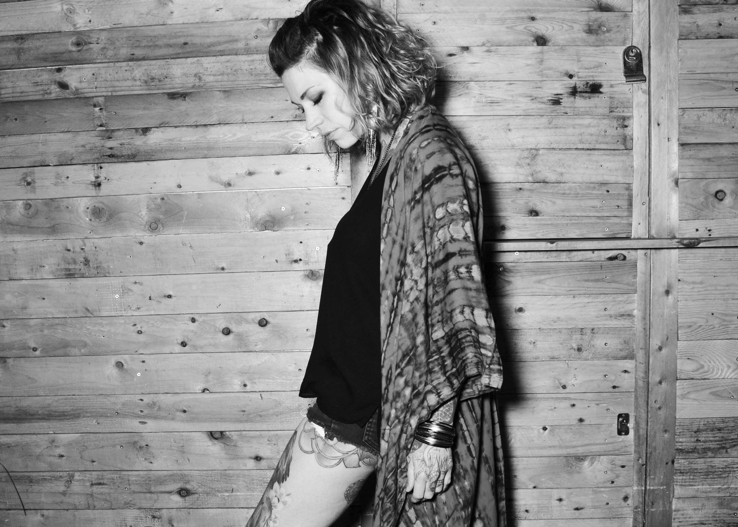 Model wearing a tie dye kimono against a wooden background in a bar with bohemian hair and styling 