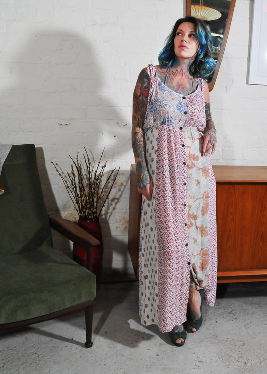 Model standing up wearing a pink patchwork floral cotton dress with blue hair in a seventies retro setting 